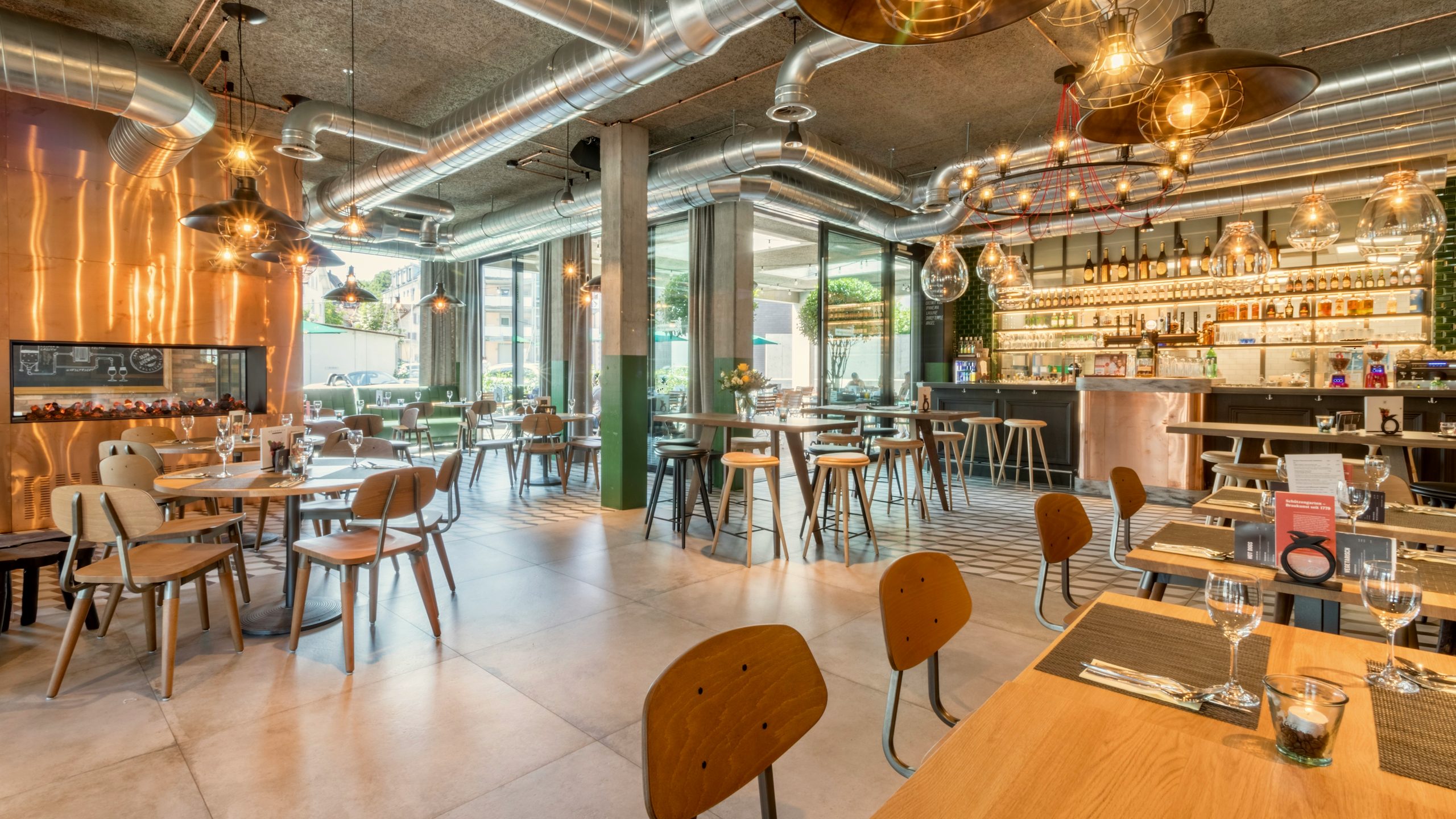Industrial restaurant with copper wall, timber tables, upholstered chairs and stools