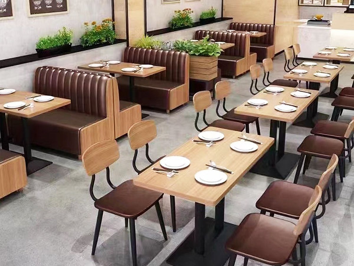 Restaurant dining room: rectangular tops on twin-column bases, set against banquettes and loose chairs.