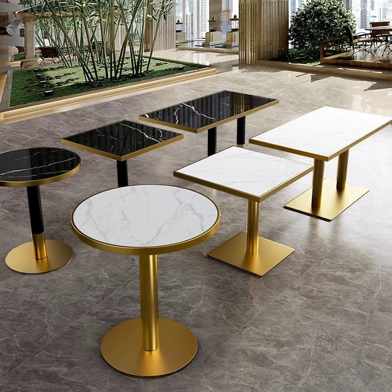 Commercial metal dining tables with gold stainless steel pedestal bases and marble-effect tops